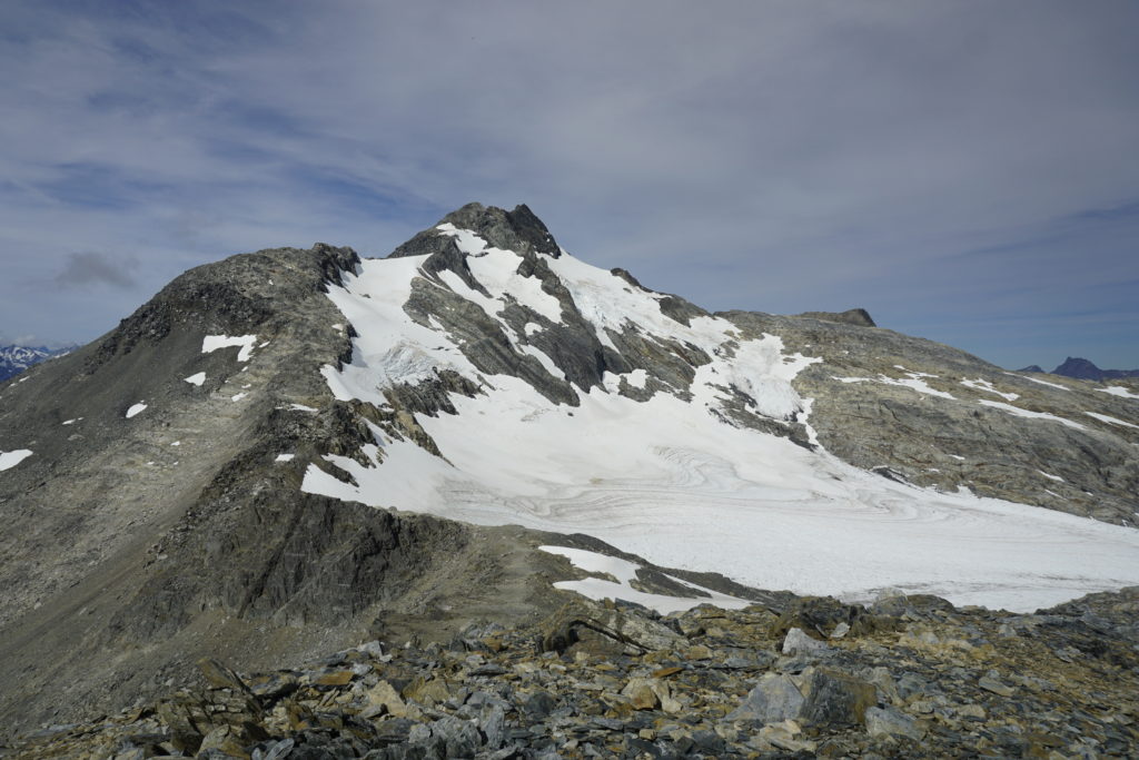 Grey allpine terrain with a white glacier in center